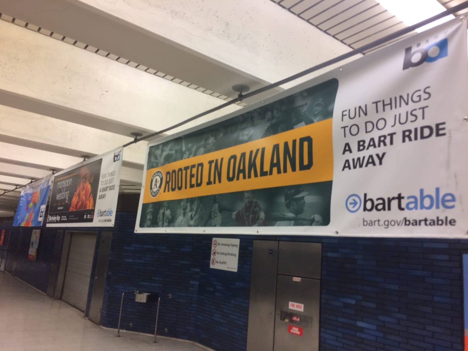 BARTable branding on hanging station banners promoting Oakland destinations.